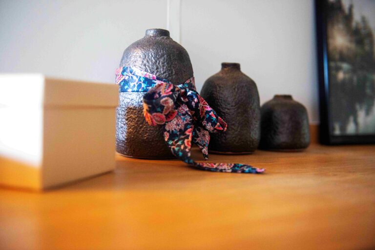 Détail déco du projet Dressing chic par Bulle Intérieure : vases en céramique sombre sur une commode en bois, avec foulard coloré en accent.