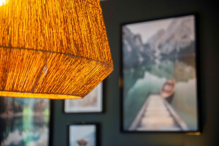 Détail du projet Dressing chic par Bulle Intérieure : suspension en fibres naturelles diffusant une lumière chaleureuse, avec en arrière-plan des cadres muraux