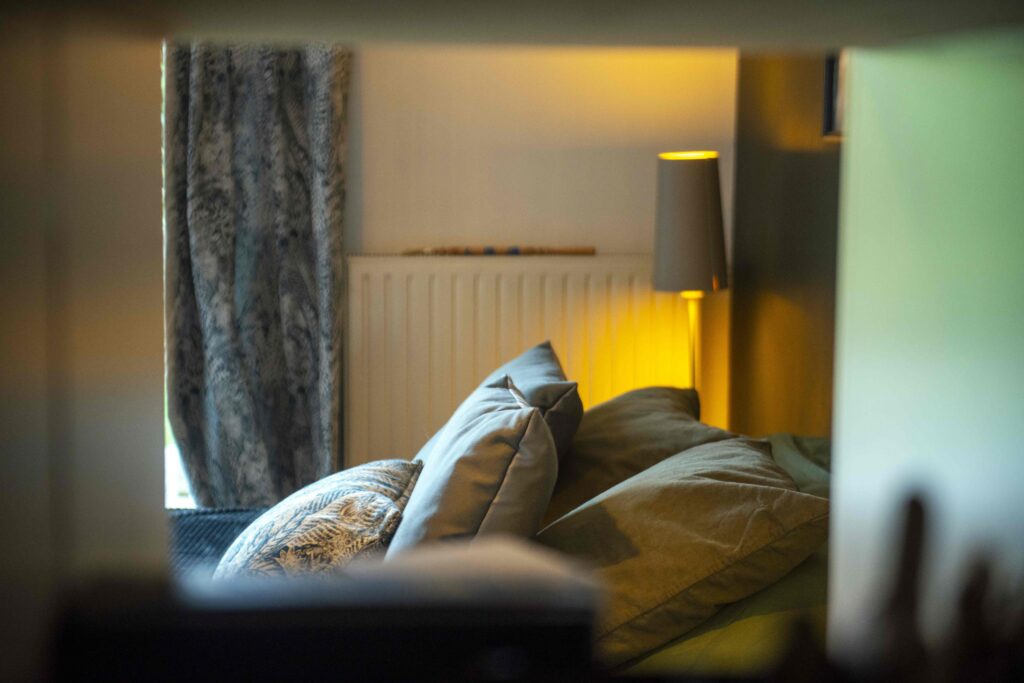 Ambiance cosy du projet Dressing chic conçu par Bulle Intérieure, avec coussins élégants, rideaux texturés et lumière tamisée d’une lampe