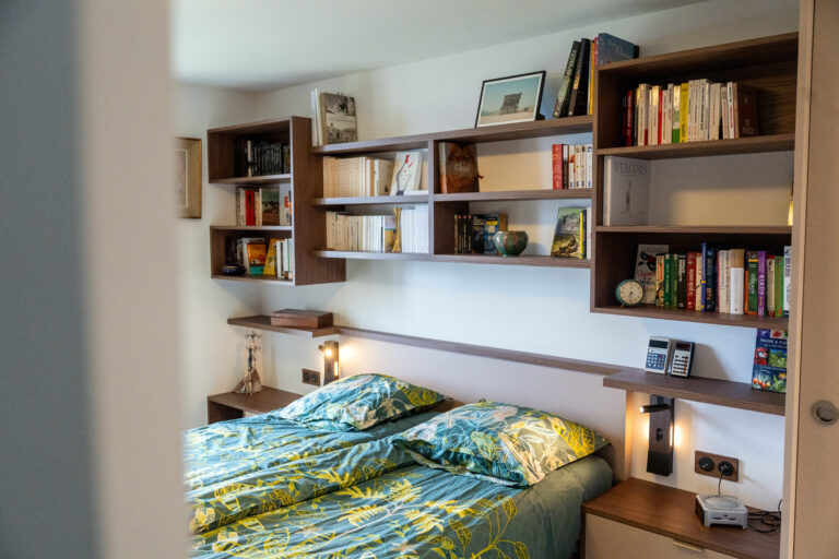 Tête de lit sur-mesure intégrant bibliothèque et rangements dans une chambre rénovée à Saint-Nizier-du-Moucherotte.