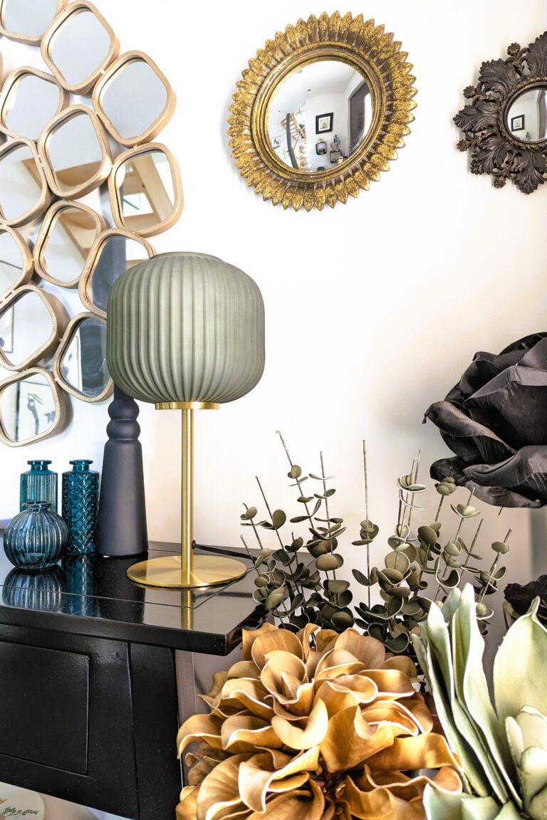 Aménagement d’entrée décoratif avec accumulation de miroirs dorés, objets de caractère et contraste de textures sur console noire