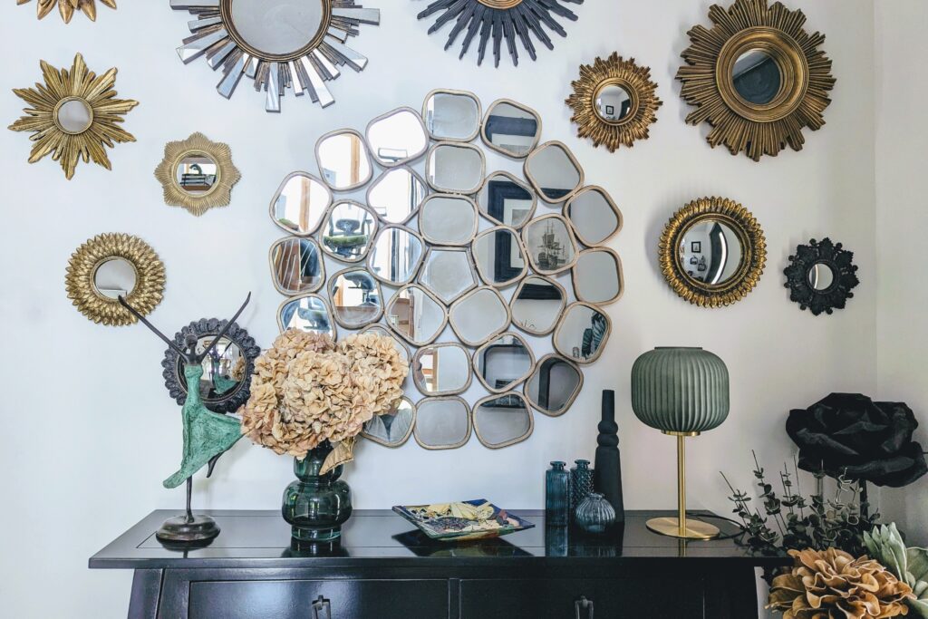 Aménagement d’entrée chaleureux avec console noire, miroirs dorés, lampe design et bouquet séché sur fond mural blanc