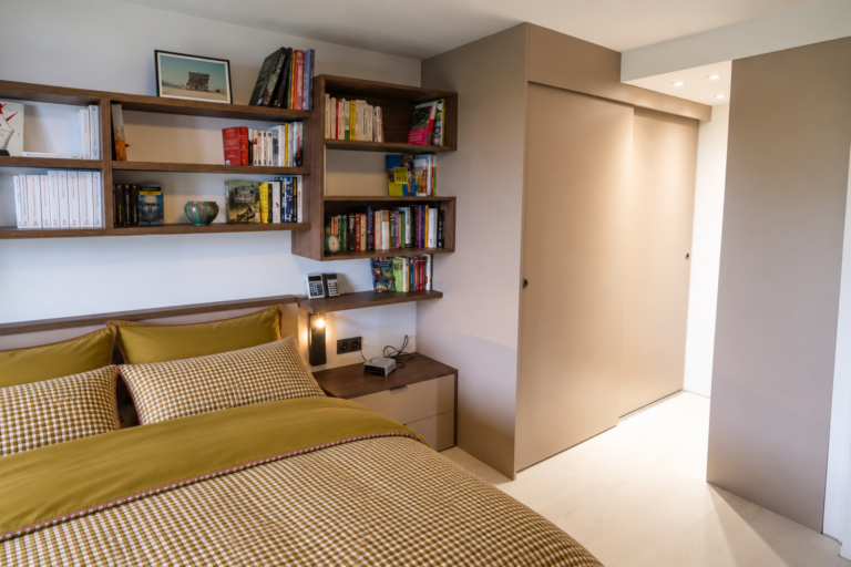Aménagement d'une chambre avec bibliothèque en bois sur mesure et dressing fermé par des portes coulissantes à Saint-Nizier-du-Moucherotte.