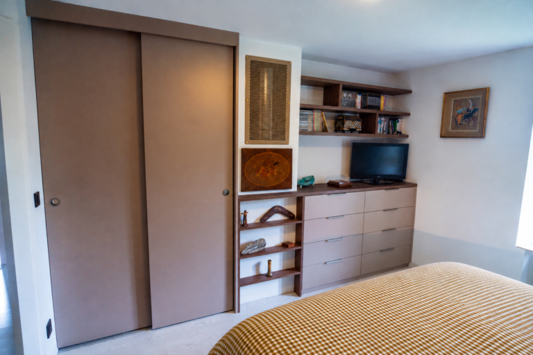 Aménagement d'une chambre avec dressing à portes coulissantes, commode sur mesure, niches ouvertes et espace télévision à Saint-Nizier-du-Moucherotte.