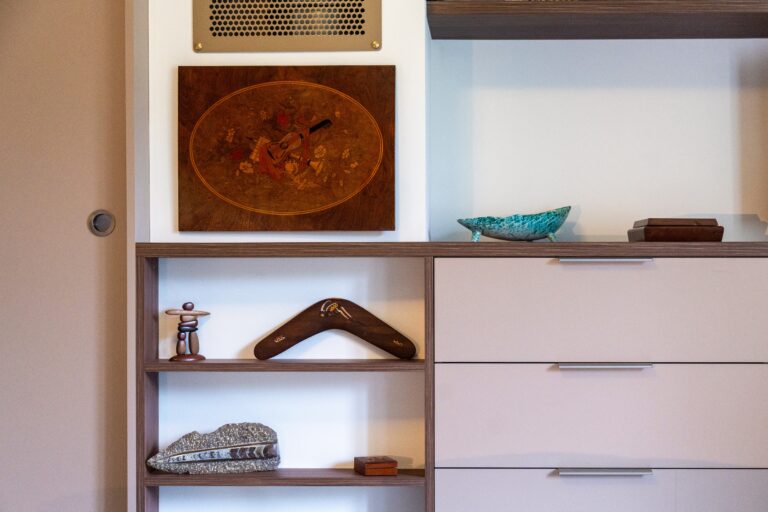 Détail d'un meuble sur mesure associant niches décoratives ouvertes en bois et tiroirs fermés aux façades claires dans une chambre du Vercors.
