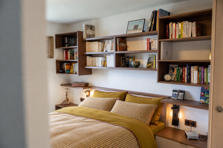 Tête de lit bibliothèque sur mesure en bois, avec étagères suspendues, chevets intégrés et liseuses dans une chambre à Saint-Nizier-du-Moucherotte.