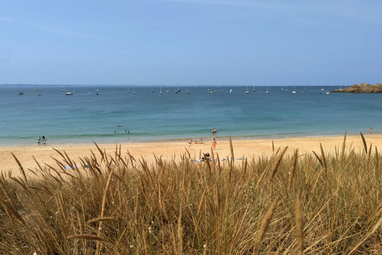 Vue d’une plage bretonne avec sable doré, mer calme et horizon marin structurant le paysage.