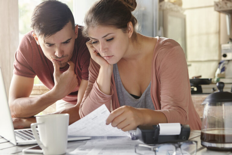 Couple préoccupé examinant des devis de rénovation, illustration des erreurs de budget sur un chantier