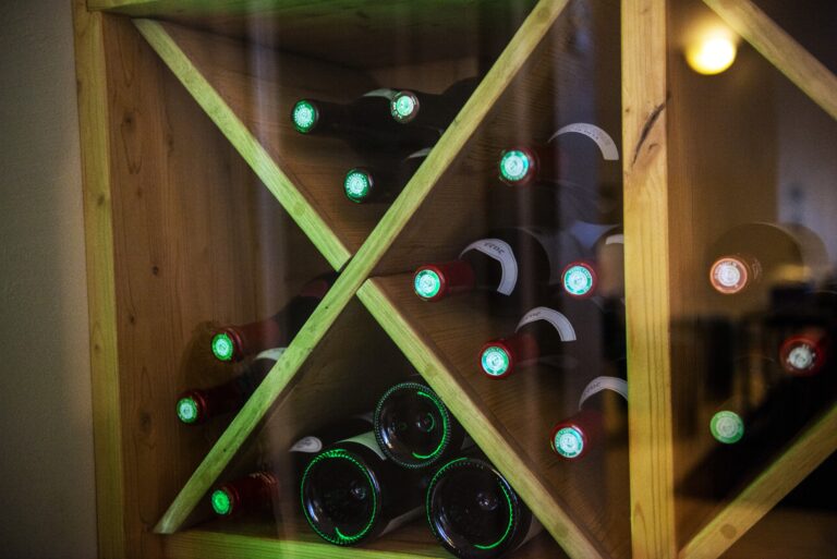 Détail du jeu de lumière sur les matériaux bois et métal de la cave à vin sous escalier.