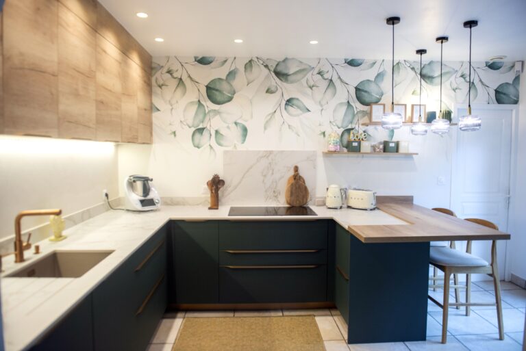 Cuisine moderne en L avec façades vert émeraude, plan de travail bois et papier peint végétal