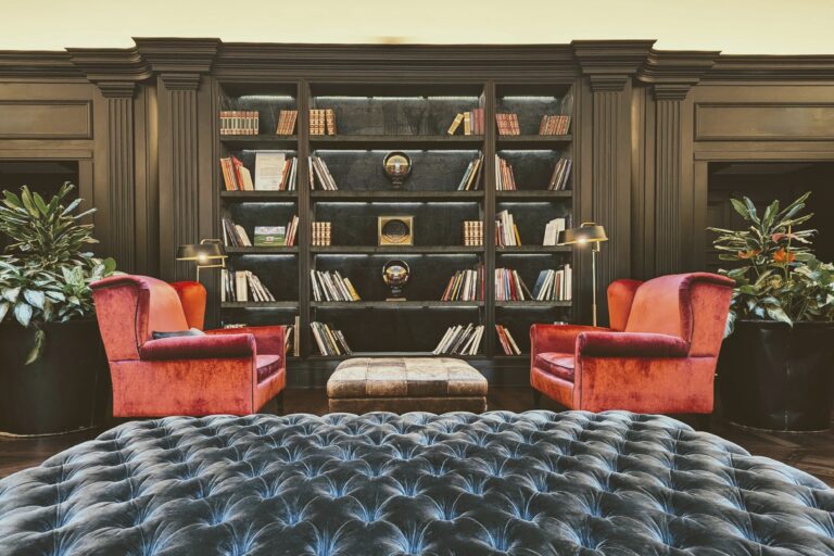 Intérieur chaleureux avec bibliothèque intégrée, fauteuils en velours et ambiance raffinée, illustrant le potentiel d’un projet de rénovation abouti.