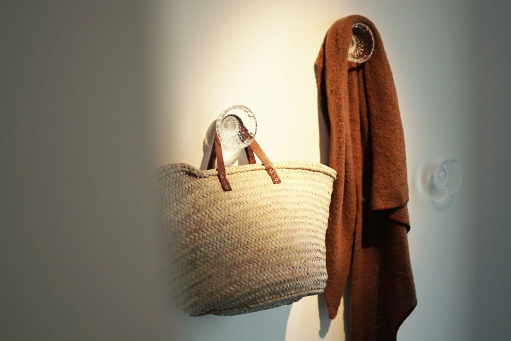 Entrée de maison avec panier, manteau suspendu et lumière naturelle, illustrant les usages du quotidien et l’importance d’un espace d’accueil bien pensé