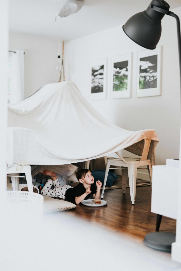 Enfant jouant dans une cabane improvisée au cœur du salon, illustrant la qualité d'usage d'un logement au-delà de sa surface.