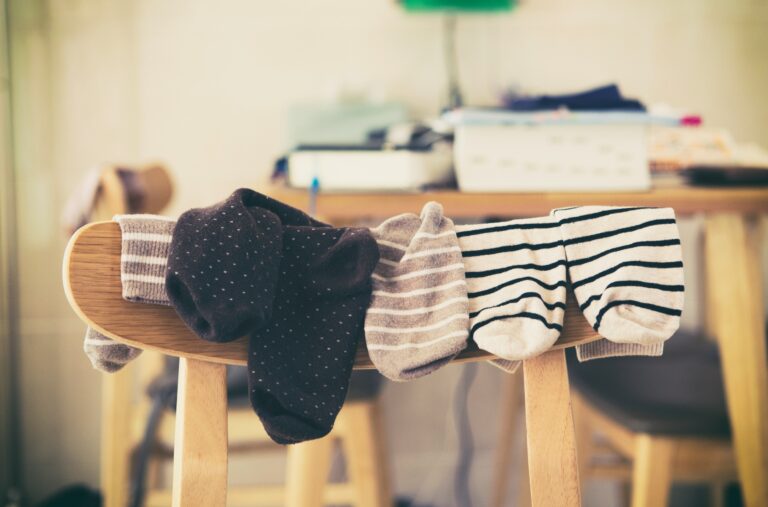 Chaussettes posées sur le dossier d'une chaise, illustrant les habitudes du quotidien qui révèlent un intérieur peu adapté aux besoins de ses occupants.